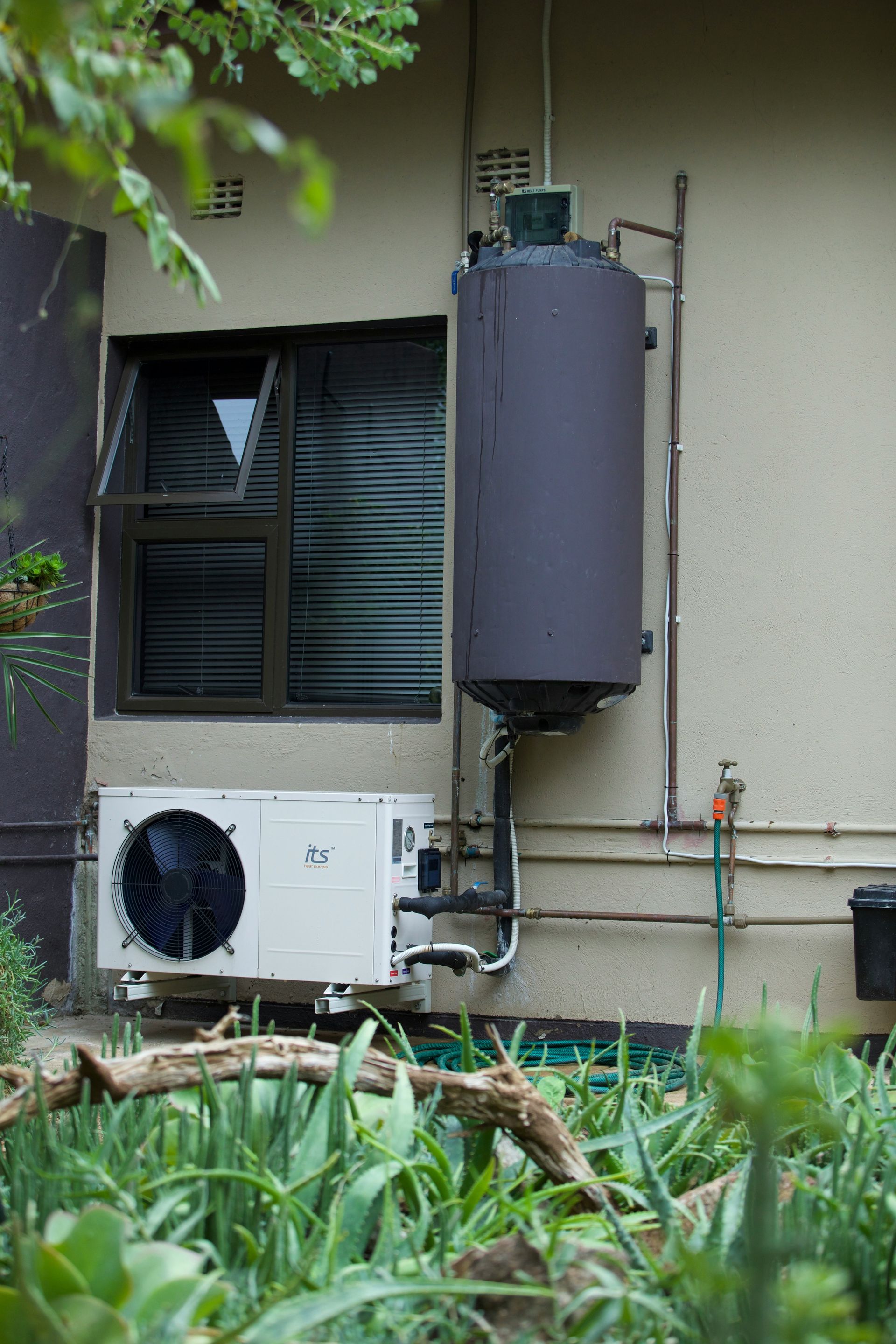 Residential water heater and air conditioner on an exterior wall.