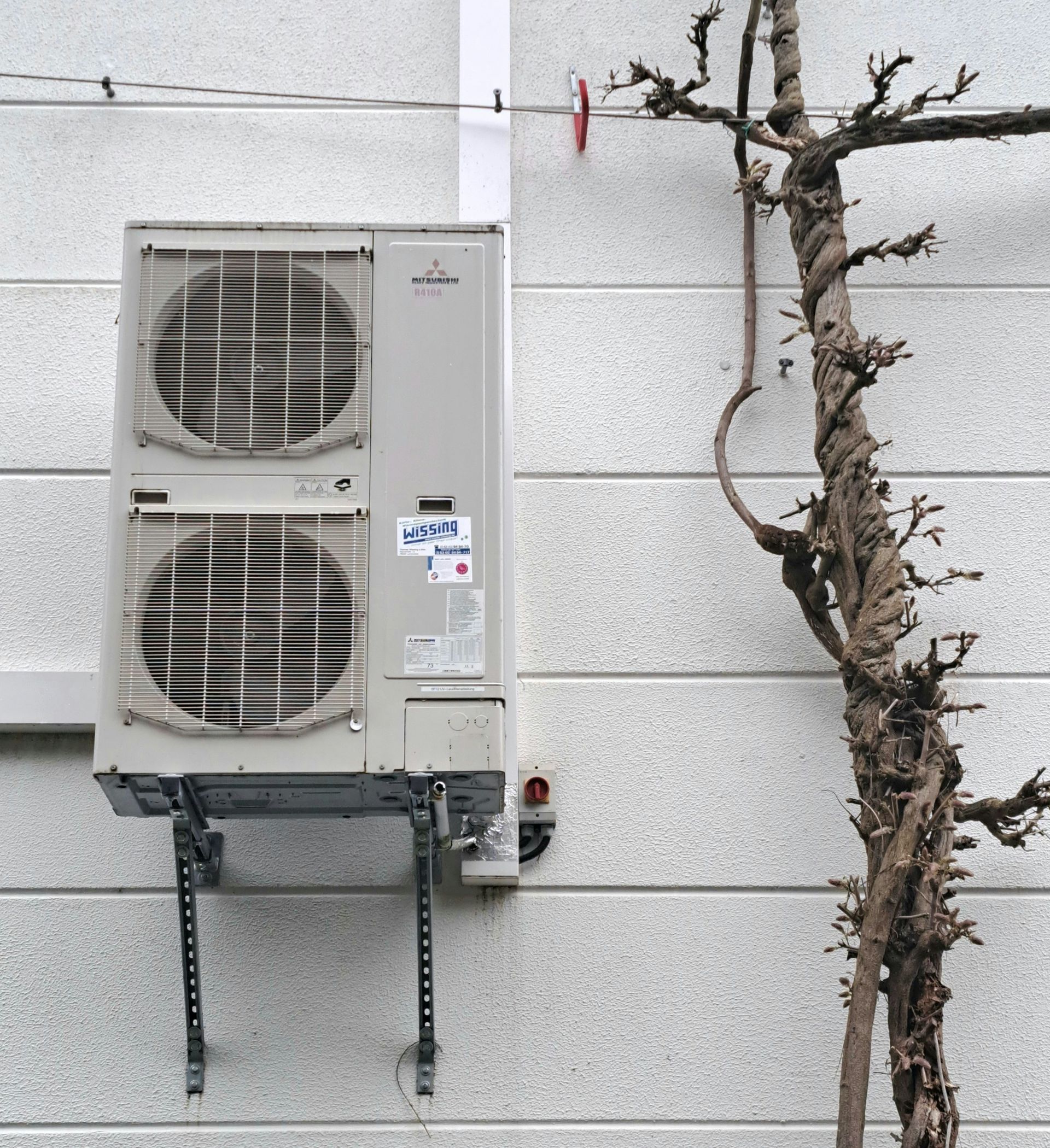a wall mounted air conditioner next to a tree