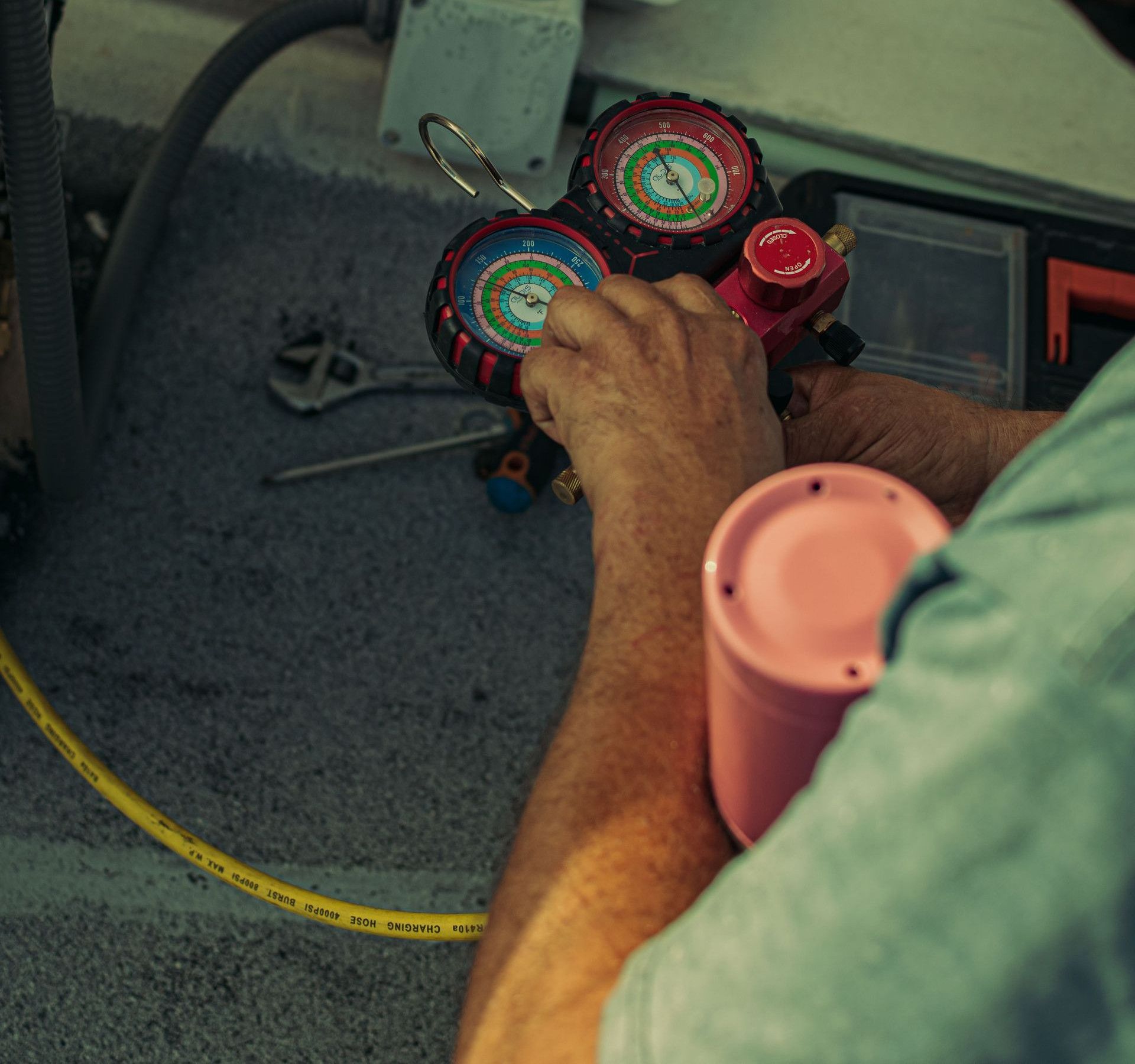 Professional technician adjusting a refrigerant manifold gauge for air conditioning maintenance.